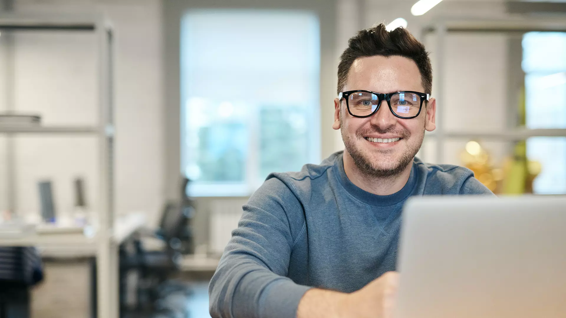 ambiente de trabajo y un colaborador de frente y sonriendo.